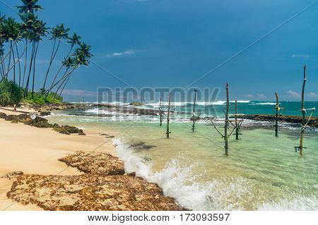 Sunny beach near Koggala - Sri Lanka The area famous for its distinct stilt fishermen, who erect a single pole in the chest-deep water on the beach, just few meters off-shore. Splittoned, vivid image.