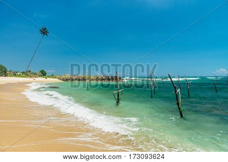 Sunny beach near Koggala - Sri Lanka The area famous for its distinct stilt fishermen, who erect a single pole in the chest-deep water on the beach, just few meters off-shore. Splittoned, vivid image.