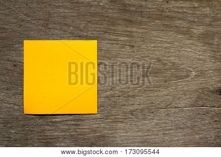 Blank orange note paper attach on brown wooden background for memo or remind