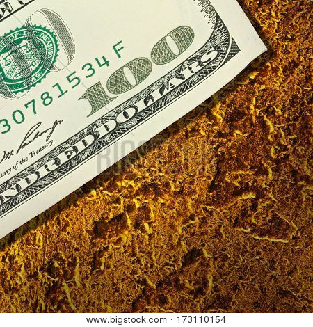 One hundred dollar banknote on golden surface texture