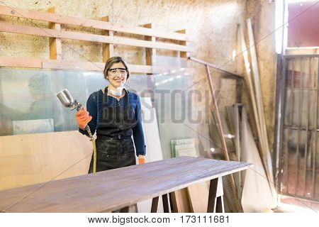 Cute Female Carpenter Using Spray Gun
