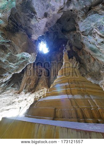 Light rays beams entering yathaypyan cave shading light on golden stupa inside