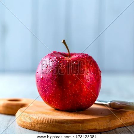 Ripe red Apple lying on a wooden Board. Apple in the water droplets. Knif on a background. Healthy food concept