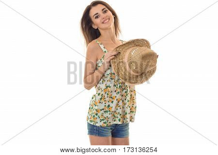 young cheerful girl in sarafan with floral pattern and straw hat looking and smiling on camera isolated on white