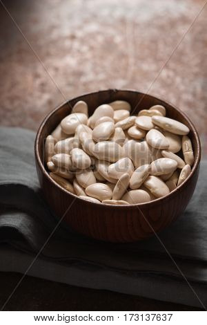 Large white beans in a wooden bowl side view vertical