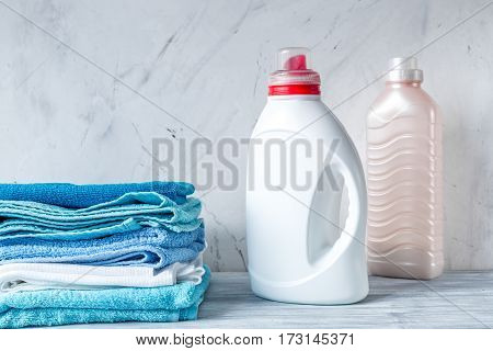 laundry set with bright towels and plastic bottels of detergent on gray table background mock up