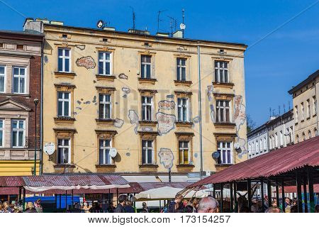 KRAKOW POLAND - 15TH OCTOBER 2016: Old architecture at Plac Nowy showing patches in the brickwork. Market stalls and people can be seen in the foreground