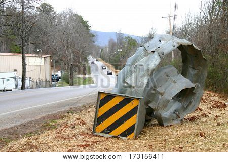 the site of an accident leaves a curled and mangled guardrail by the side of the highway