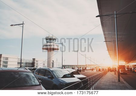 Parking lot road and cabstand near modern contemporary airport terminal in front of air traffic control tower with many passengers and staff passing in distance Barcelona Spain