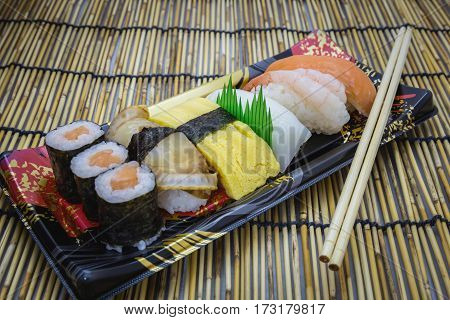 Sushi set sashimi and rolls served on traditional plate and mat
