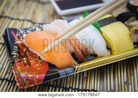 Closeup of sushi set sashimi and rolls served on traditional plate and mat