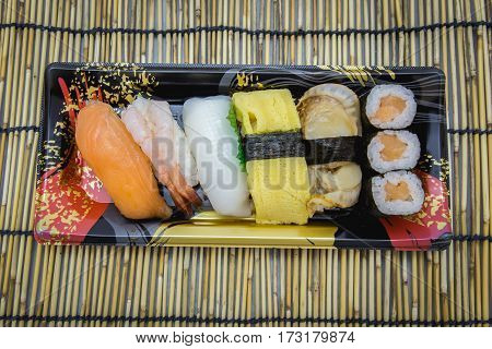 Sushi set sashimi and rolls served on traditional plate and mat