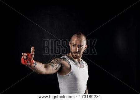 Fighter show by finger. Bearded man point the way. Sport concept with strong body guy in white t-shirt. Copy space for advertising fitness pruduct.