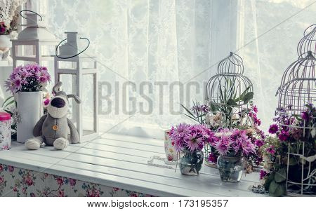 Provence style interior-beautiful pink and purple bouquets in vase and cages over window. Light home decoration with flowers asters chrysanthemums. Retro living room. Vintage holiday floral concept.