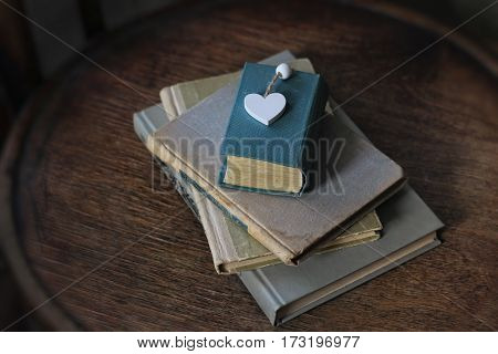 old book and heart lying on a wooden surface.