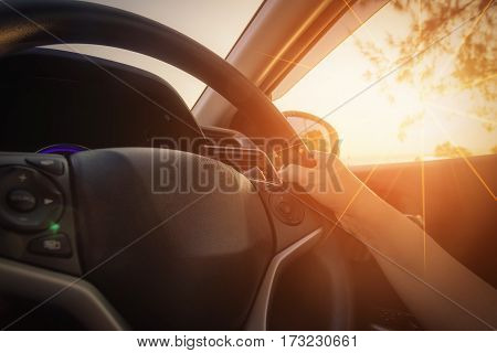 Close-up Of Woman's Hand Holding Steering Wheel with lens flare.