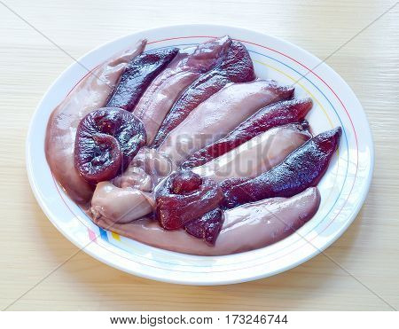 bags raw eggs and milt of herring lie in ceramic white plate on a wooden table