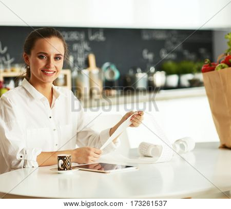 Young woman planning expenses and paying bills on her kitchen