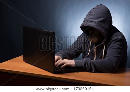 Hooded Computer Hacker Stealing Information With Laptop