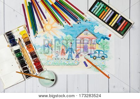 Hand drawn Bright Colorful Childrens Sketch With Happy Family, House, Dog, Car on the Lawn with Flowers with lying flat pencils, paints and pastel - concept of children creativity, close up top view