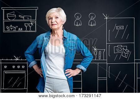 Absolutely spotless. Happy delighted aged woman standing in the kitchen and smiling while being proud of the cleanness in the room