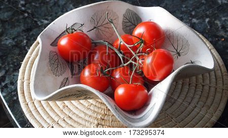 Sunlit bowl of ripe cherry tomatoes on a vine