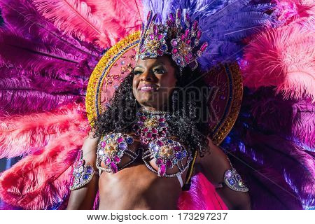 MOSCOW, RUSSIA- JANUARY 2017: Brazilian carnival show. Beautiful girl bright colorful carnival costume dark background. Smiling Afro-Americans woman samba dancer pink carnival costume black background