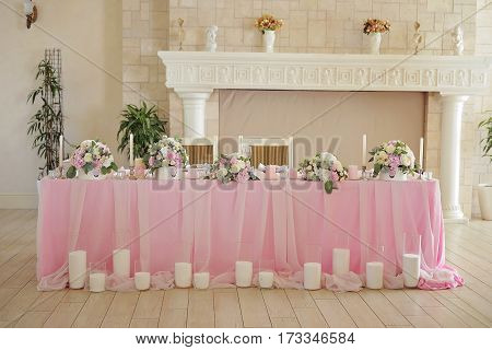Luxury decorated marriage couple table with flowers decorating, candles and pink tenderless cloth