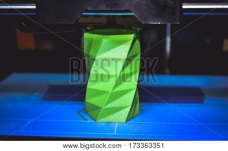 3D printer works and creates an object from the hot molten plastic close-up. Automatic three dimensional 3d printer performs plastic green colors modeling in laboratory.