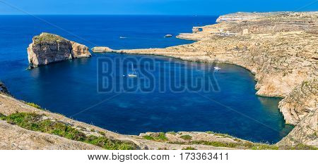 Gozo Malta - Panoramic skyline view of Dwejra bay with Fungus Rock Azure Window and sailboat on a nice hot summer day