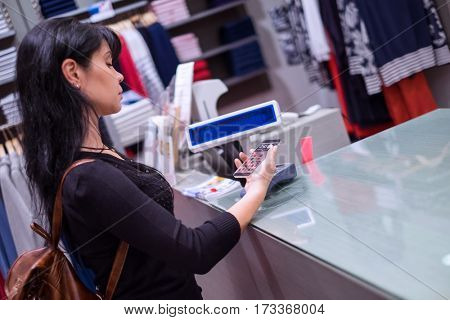Girl pays to shop using mobile phone. NFC - Near field Communication. Mobile payment PayPass.