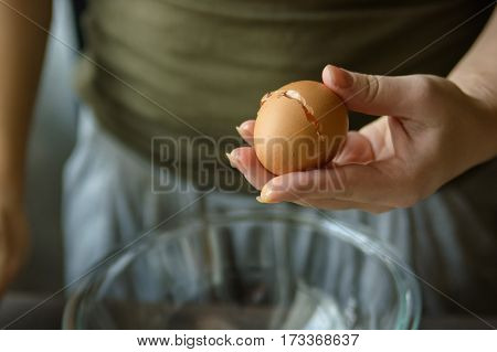 Close-up of woman's hands breaking egg during cooking