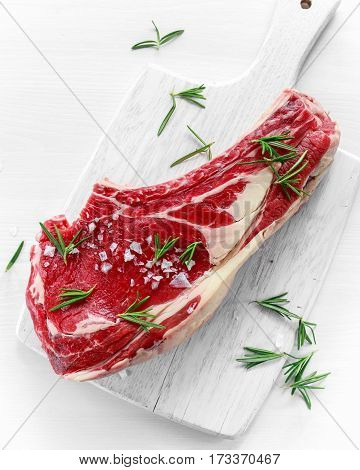 Fresh Raw Beef bone rib roughly choppid on white board with herbs.