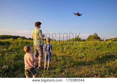 Father and son controls RC drone quadrocopter in the sky
