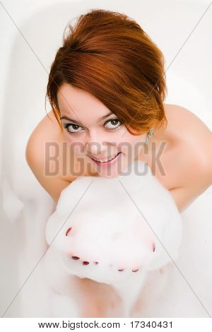หญิงสาวยิ้มเปลือยในอ่างอาบน้ำกับ soapsuds ในมือ