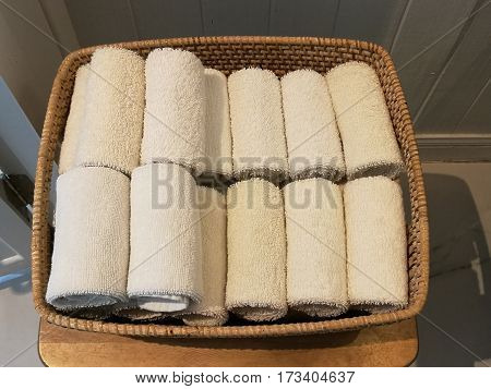 Pile of cloth hand towel table napkin handkerchief on the basket in spa bath room toliet with blur white wooden wall background topview