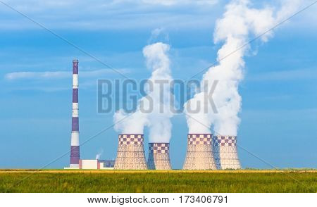 Thermal power plant рigh pipe with cooling towers on a green meadow