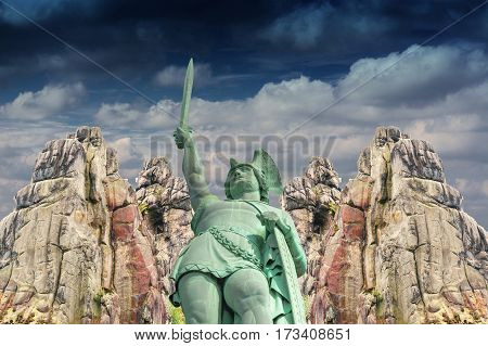 Curious and mysterious; Hermann Monument in the background the Externsteine before dramatic sky.