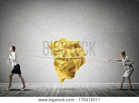 Two businesswomen playing tag of war game