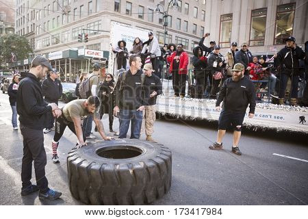 NEW YORK - 11 NOV 2016: US Marine veteran Guy Valentino attempts the Guinness World Record for fastest one mile tire flipping of 450lb tire on 5th Ave at the Americas Parade on Veterans Day.