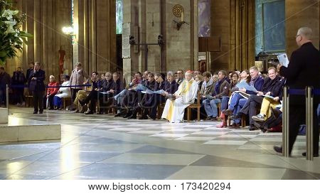 Paris, France - October, 14, 2016: Notre Dame de Paris cathedral interior with prayers listening a sermon from a French cardinal Andre Vingt-Trois.