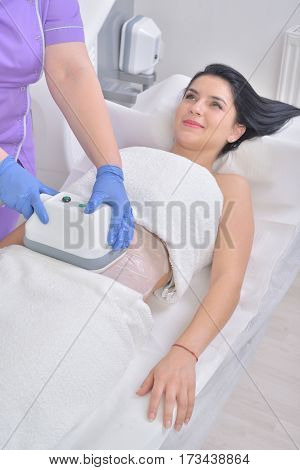 Pretty young woman getting cryolipolyse fat treatment in professional cosmetic cabinet