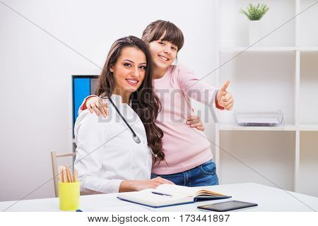 Portrait of female doctor and child showing thumb up.