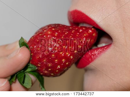 Sexy lips young woman and red strawberry