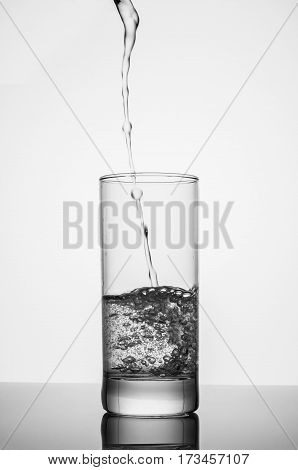 pouring sparkling water on glass on white background