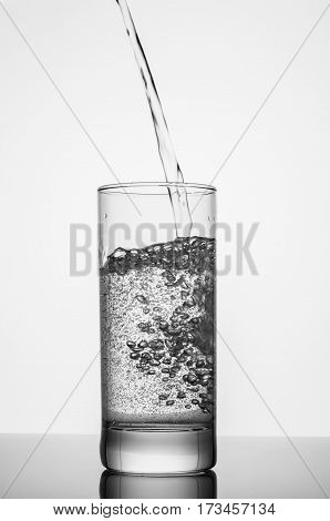 pouring sparkling water on glass on white background