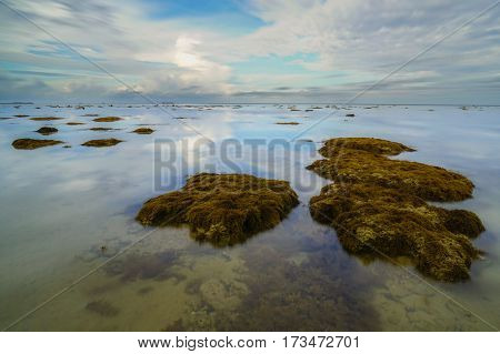 Calm sea,reflection and cloudy sky during low tide. Reflection of the vibrant sky and moving cloudy.