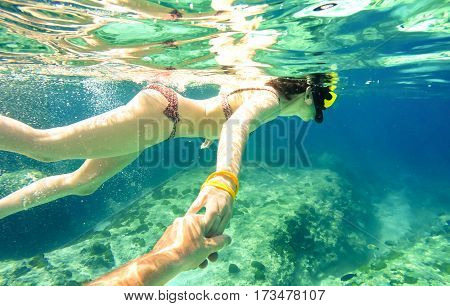 Snorkel couple swimming together in tropical sea with follow me composition - Snorkeling tour in exotic diving scenarios - Fun travel concept with active girl underwater - Soft focus due water density