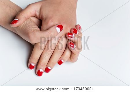 Close-up shot of young femle hands with red and white nail manicure. Copy space.