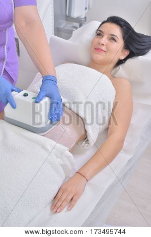 Pretty young woman getting cryolipolyse fat treatment in professional cosmetic cabinet